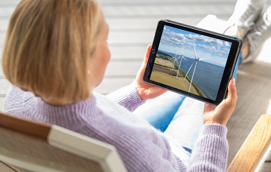 Magdalena Neuner sitzt im Sessel und schaut sich auf einem Tablet die Pangaea Life Investmentreise an